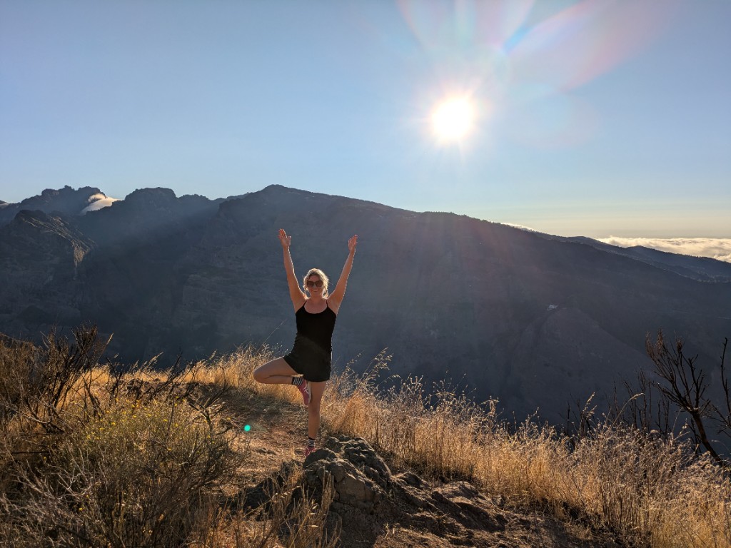 Holly practising tree pose on a mountain ridge at sunrise